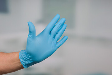 Doctor's hand in medical gloves makes a STOP/THUMBS-UP gesture 