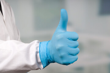 Doctor's hand in medical gloves makes a THUMBS-UP gesture 