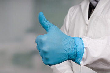 Doctor's hand in medical gloves makes a THUMBS-UP gesture 
