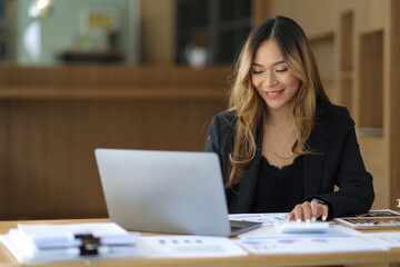 Portrait of a business woman working or secretary with laptop and financial documents on the desk in the office.
