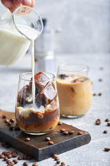 Ice coffee in glass. Ice coffee served in glass with coffee ice cubes and milk cream on table.