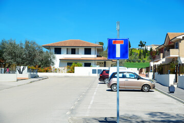 Suburban street with traffic sign No Through Road and car parking lot on sunny day