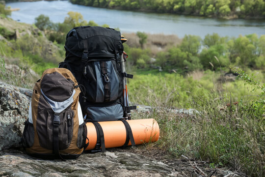 Backpacks with trekking poles and camping mat on rocky hill, space for text © New Africa