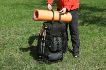 Hiker fastening mat on backpack outdoors, closeup