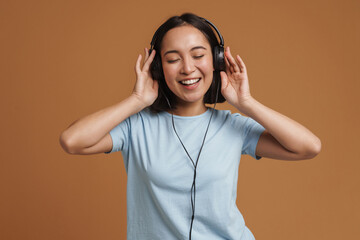 Young asian woman in headphones dancing while listening music