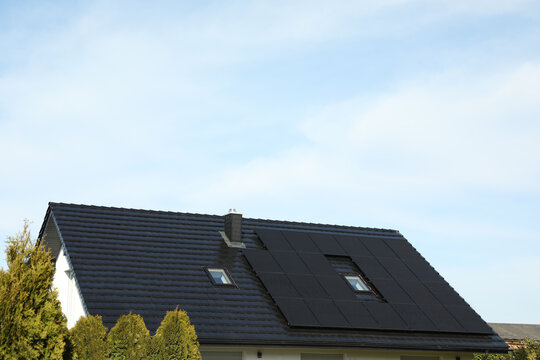 House with installed solar panels on roof, space for text. Alternative energy