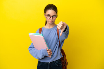 Student kid woman over isolated yellow background showing thumb down with negative expression