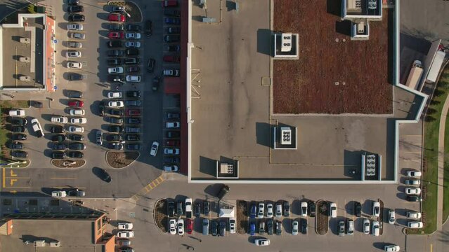 Aerial geometric top view of the grocery food store plaza, supermarket or shopping mall parking lot with lots of cars moving in and out. Time lapse or hyper lapse.
