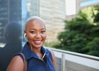 A young Black businesswoman arrives at the office with headphones