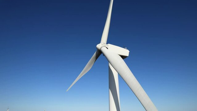 Aerial close up shot of wind mills turbine rotating by the wind and generating renewable green energy. Closeup of a wind turbine during golden hour sunset. Energy alternative and environment ecology.