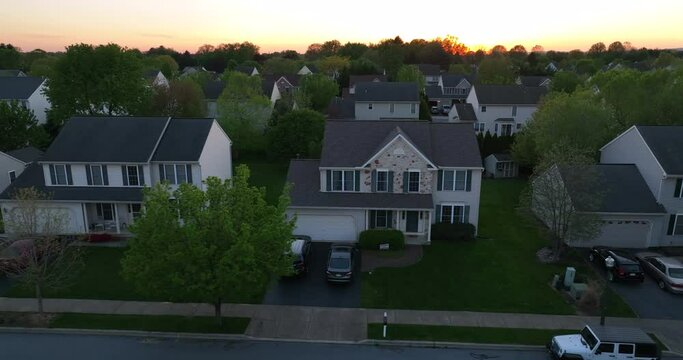 Houses in neighborhood at springtime. Aerial truck shot of homes during sunset. Establishing shot of new housing development in suburban America.