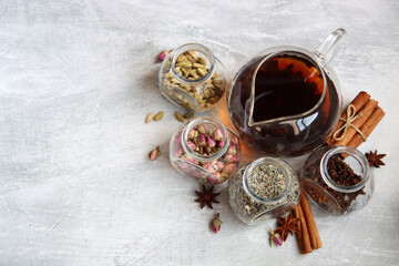 Still life with tea pot and glass jars of spices. Black tea, clove, cardamom. cinnamon, anise stars and lavender top view photo. Traditional spiced tea. 
