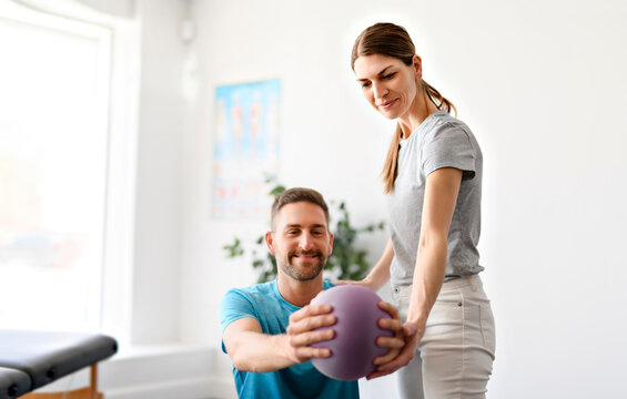 Modern rehabilitation physiotherapy woman worker with man client with ball