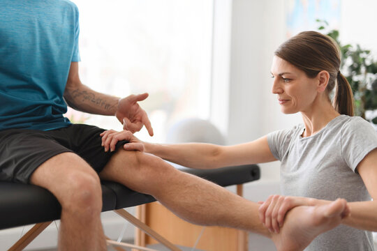 Modern rehabilitation physiotherapy woman worker with man client leg treatment
