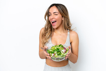 Young caucasian woman isolated on white background holding a bowl of salad while winking