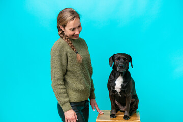 Young caucasian woman with her dog isolated on blue background with happy expression