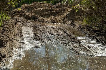 Tractor tracks in the mud. Large dirty puddle filled the hole after the tractor. No road. Ground water.