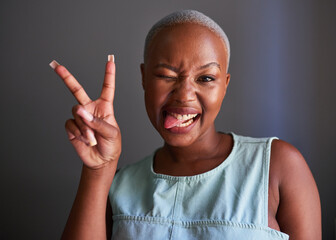 A young Black model with shaved hair poses peace sign and tongue out