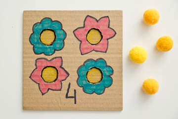 Hand made children home activity from cardboard and pom poms. Early education, Montessori methodology. Implement to develop fine motoric skills, logical thinking learn counting.