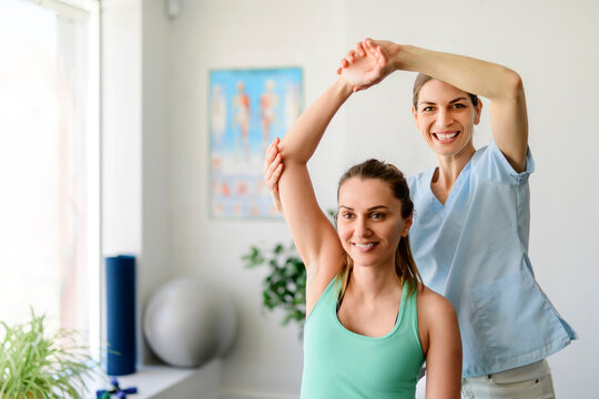 Modern rehabilitation physiotherapy woman worker with woman client shoulder treatment