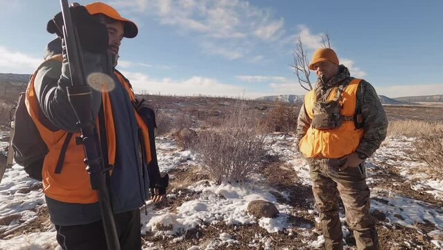 Two hunters discuss strategies for deer hunting in winter. outdoor activities.
