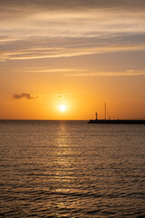 Fototapeta na wymiar Sunset over Mykonos island, Cyclades, Greece. Lighthouse, orange yellow sky sparkle sea. Vertical
