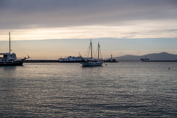 Cyclades, Greece. Moored boat at Mykonos island port, rippled sea, sky in the dusk background.