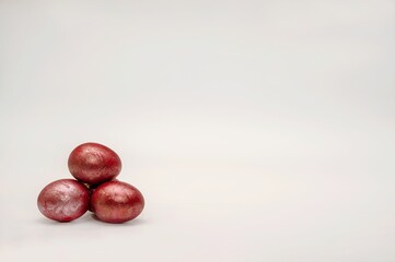 On the religious holiday of Easter, three beautiful chicken eggs hand made painted in different red colours, situated horizontal view