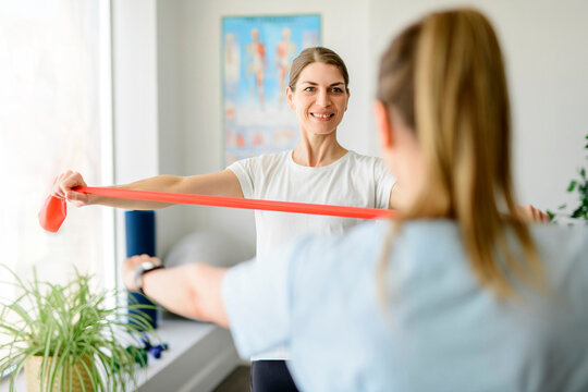 Modern rehabilitation physiotherapy woman worker with woman client using elastic
