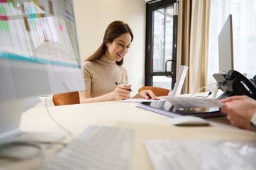 Female client filling out questionnaire while sitting at the reception desk of a medical clinic or an office building of social security financial aid department