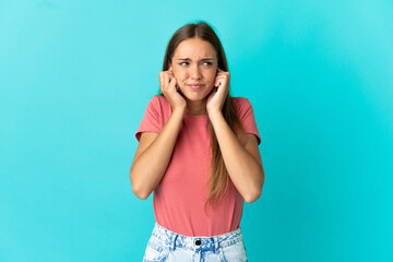 Young woman over isolated blue background frustrated and covering ears