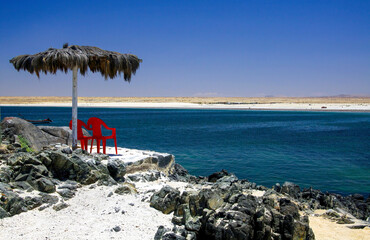 Beautiful relaxing tropical desert sea lagoon landscape, two red empty isolated chairs, palapa tiki...
