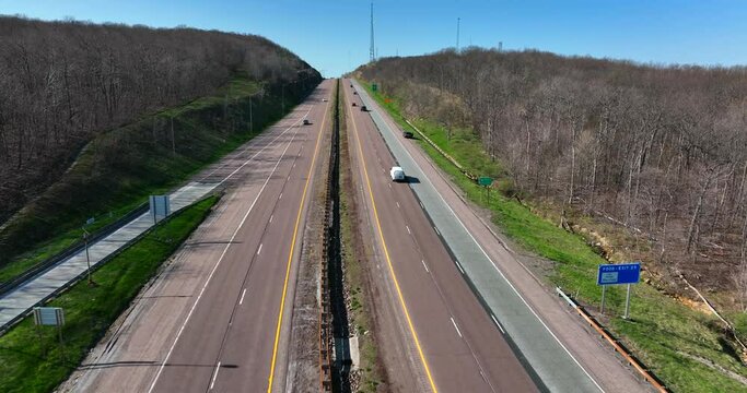 Interstate highway road up hill and through Mountains. Bare trees on winter day.