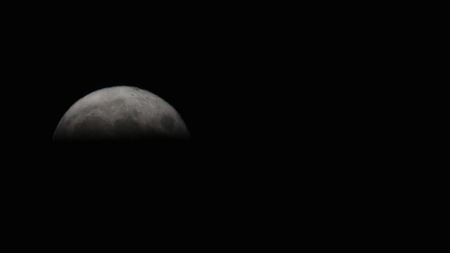Moon rising over black horizon and sky, haze atmosphere