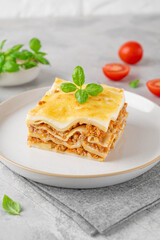 Slice of Lasagna bolognese with meat sauce and bechamel with melted cheese on top and fresh basil. Italian cusine. Copy space.