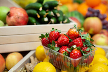 Tray of strawberries on the counter of a vegetable store among vegetables and fruits.