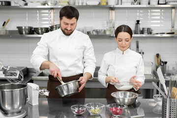 Pastry chef a man and a woman in a professional kitchen prepare a sponge cake, mix the ingredients...