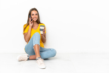 Young girl sitting on the floor holding coffee to take away and a mobile