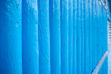 Vertical log wall in blue, outdoors. Wooden building. 