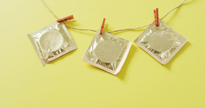 Video of close up of condoms hanging on green background