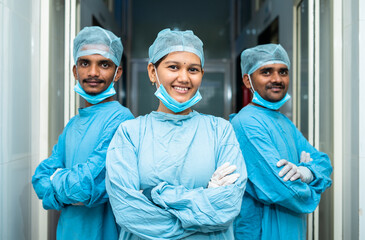 Team of young medical practitioners in operation gown confidently standing at hospital corridor -...