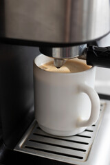 a cup of coffee in a coffee machine close-up