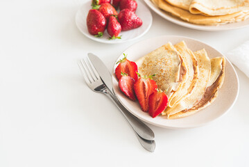 French crepes with chocolate spread and strawberries on white table