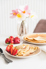 French crepes with chocolate spread and strawberries on white table