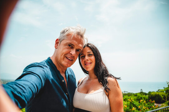 Trendy man and his beautiful girlfriend in love having genuine fun taking selfie at a seascape town tour - Wanderlust lifestyle travel vacation concept with tourist couple on sea city sightseeing