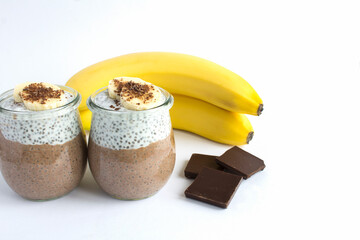 Chocolate pudding with chia seed and banana in the glass jars on the white background. Copy space.