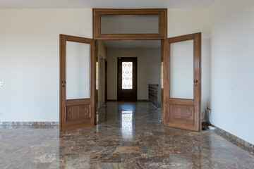 Front view of doors with glass open on the entrance. Interior of empty old villa to renovate