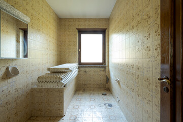 Front view bathroom with radiators for on the tub and bright window. Interior of empty old villa to renovate