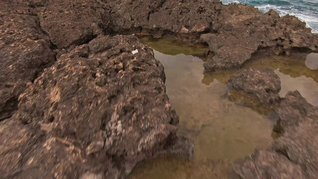 Low angle dolly forward of rock formation at Hawaiian beach