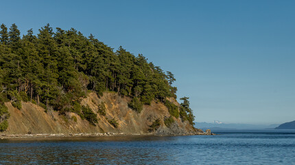 Rocky Sucia Island shore on Puget Sound with Cascade Mountains in the distance.